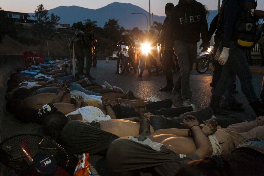 People lie on the ground after being detained for allegedly looting a supermarket on Sunday.