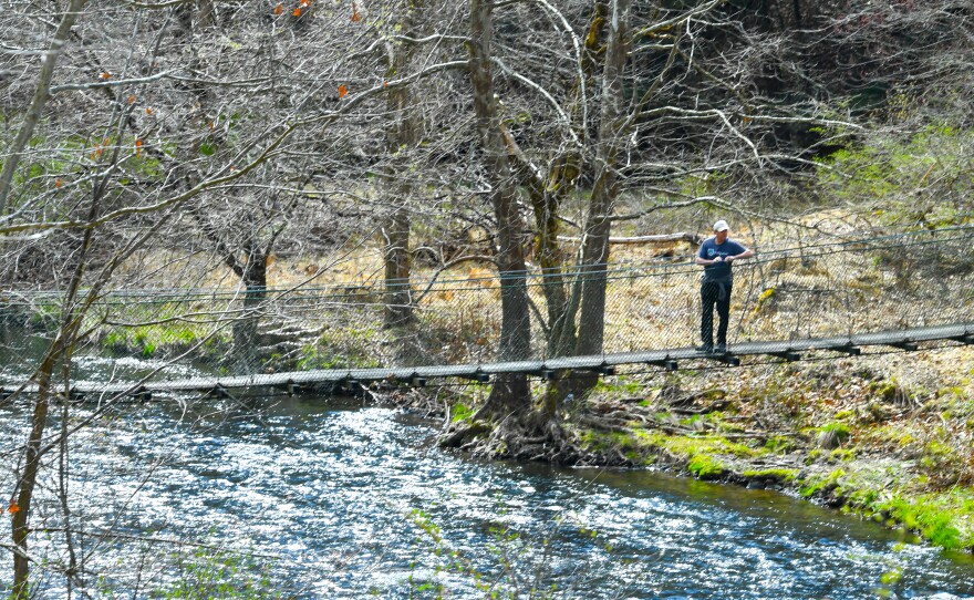 A man stops to rest on the suspension bridge over the south branch of Tunkhannock Creek that runs through Keystone College's campus.