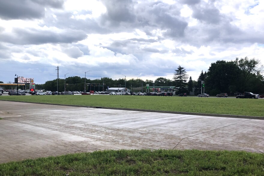 A large vacant lot sits between the traffic signals at the Peoria intersection of War Memorial Drive and University Street in the background and two access roads in the foreground.
