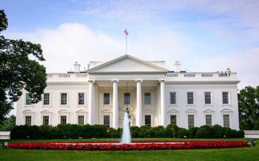Front view of the White House with fountain and red flowers in front lawn
