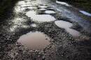 A wet rural road with bad potholes.