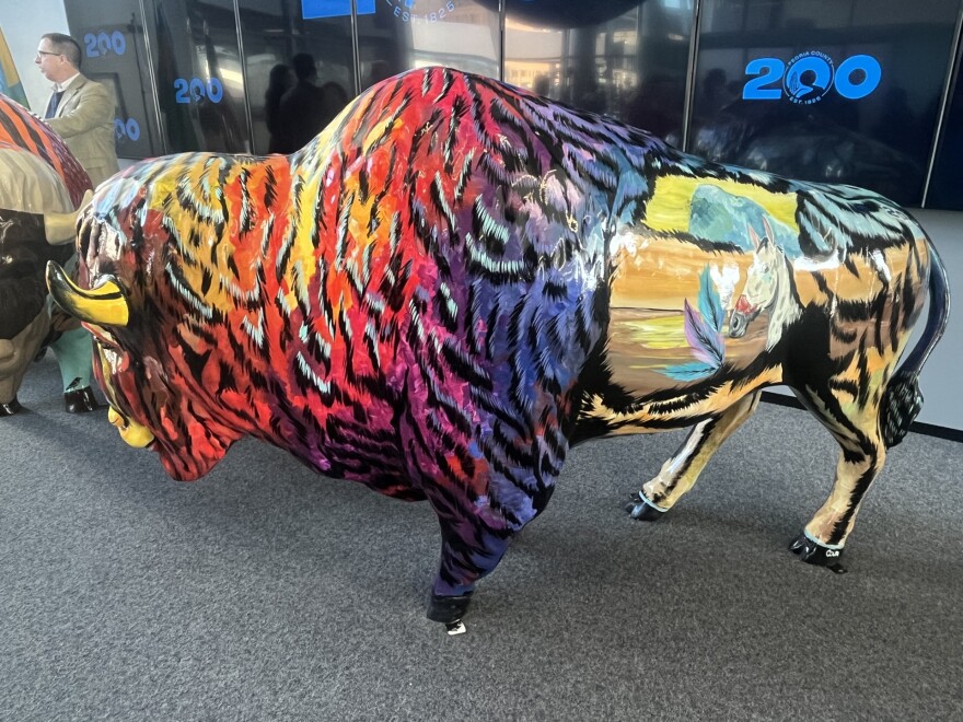 Artist Megan Couri's vibrant tie-dye bison stands in the Peoria Riverfront Museum. A painting of a horse breaks through the colors of the bison's flank.
