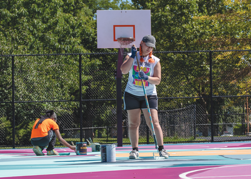 Paris Cockrell and Francheska Diaz (foreground) work to finish painting the basketball court at Roxie Ann Sinkler R-Center on Sept. 2021.