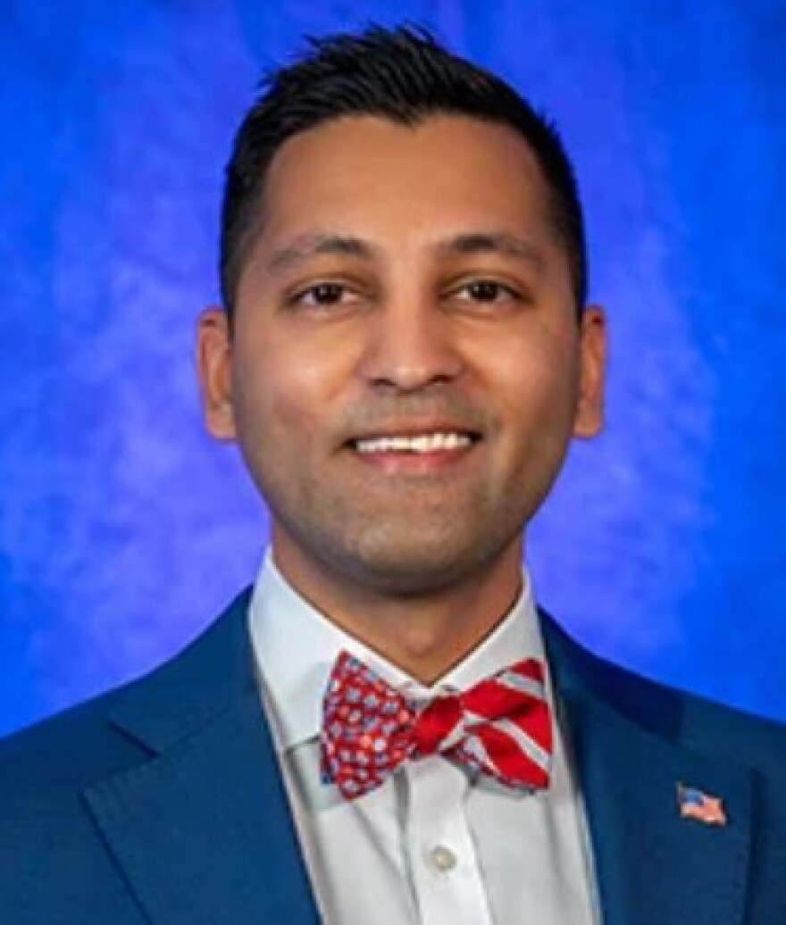 Head shot of a man with a blue suit jacket, white shirt and red bowtie