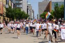 people in white tshirts hold rainbow flags while walking down the street