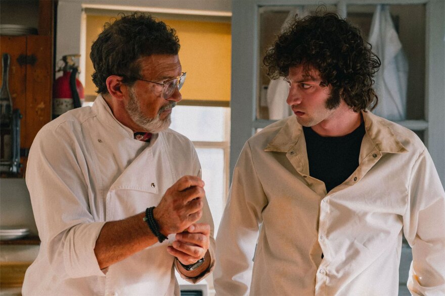 Antonio Banderas as Chef, and Dominic Sessa as a young Anthony Bourdain. Both are wearing white chef smocks