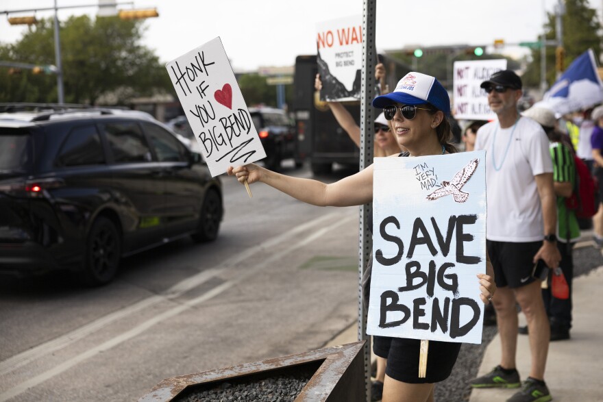 Faye Holland holds up signs outside of Yeti during a Save Big Bend protest in Austin on Saturday.