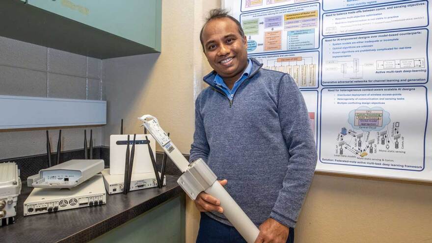 Professor poses with technology equipment.