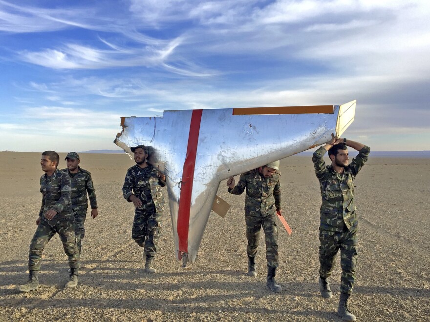 Iranian soldiers carry part of a target drone used in air-defense exercises. Iran is also turning some target drones into low-tech weapons for its proxies.