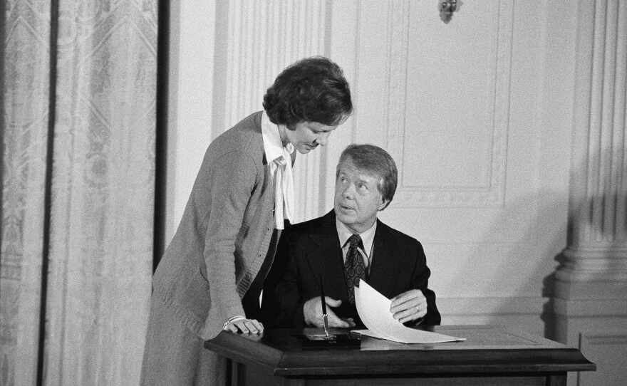 FILE - President Jimmy Carter talks with his wife, first lady Rosalynn Carter, prior to signing an executive order establishing a Presidential Commission on Mental Health, Feb. 17, 1977, in the East Room of the White House in Washington. Health care experts say the advocacy of Rosalynn Carter, who died Sunday, Nov. 19, 2023, at age 96, created a framework for much of the progress on mental illness in America. (AP Photo/Charles Tasnadi, File)