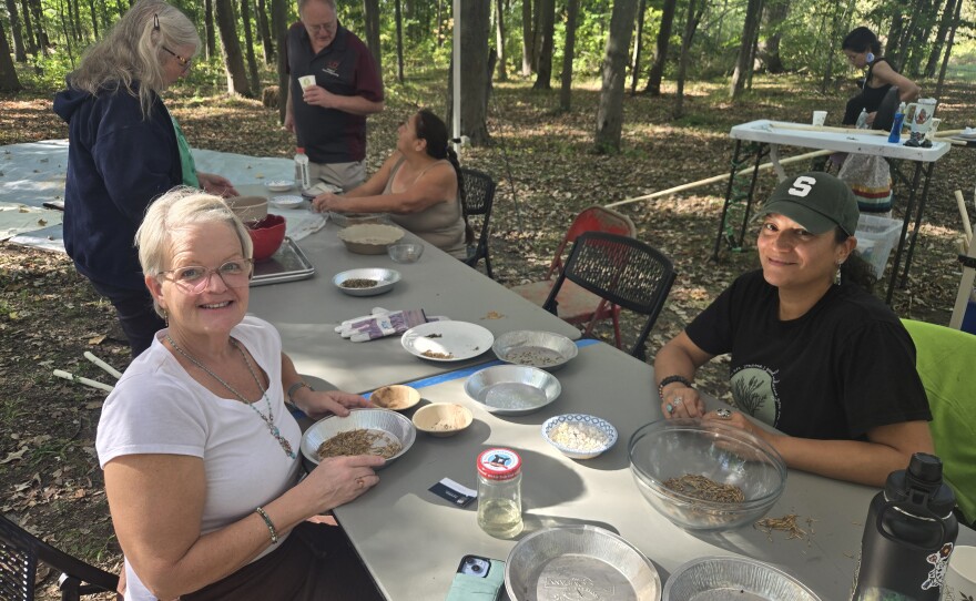Two women sitting at a table, looking up and smiling with bowls of wild rice in front of them