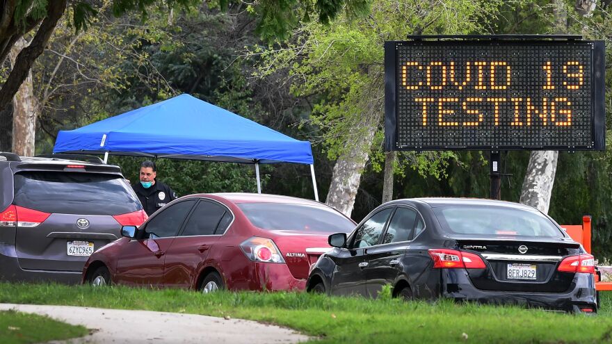 A police officer mans the entrance to a coronavirus testing center in Pacoima, Calif.