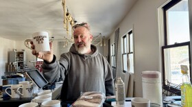 Man holds up a white mug.