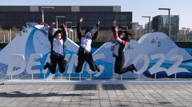 Olympic workers leap as they pose for photos with an installation near the Beijing Olympic Park at the 2022 Winter Olympics on Jan. 25, 2022, in Beijing. (Jae C. Hong/AP)