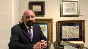 Neal Asbury stands in front of first maps of Florida at NSU exhibit.