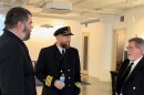 Three men wearing boat captain uniforms talk to each other.