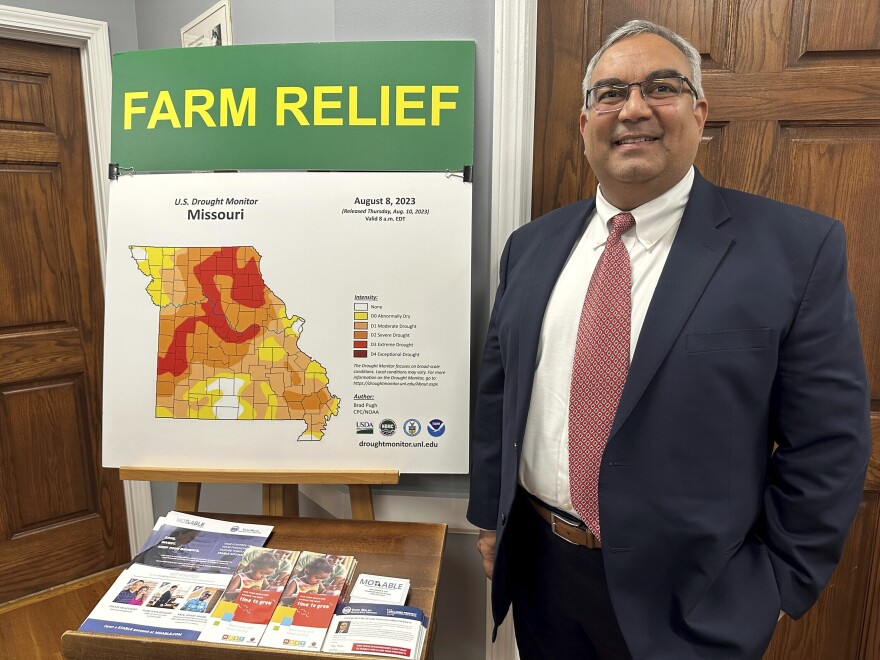 Missouri Treasurer Vivek Malek stands near a poster promoting drought conditions and state aid programs, Jan. 4, 2024, at his Capitol office in Jefferson City, Mo. Agricultural entities are among several categories of businesses that can receive low-interest loans backed by deposits of state funds made by the treasurer's office. Missouri lawmakers gave final approval Thursday, April 18, to significantly expand a low-interest loan program for farmers and small businesses. (AP Photo/David A. Lieb, File)