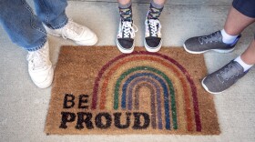A Missouri family stands by their doormat at a home they are soon to leave — drawn out by bills that would limit the freedoms of their transgender son.