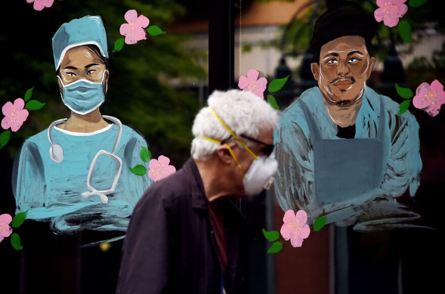 A man wearing a face mask walks past a mural in support of health workers during the outbreak of COVID-19 in Arlington, Virginia, on May 6, 2020. (Olivier Douliery/AFP/Getty Images) 