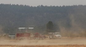 Wind kicks up dust at the fairgrounds as firefighters meet and confer about the wildfire raging on the other side of the hill behind them just outside of Las Vegas, N.M., on Saturday, May 7, 2022. Winds and wildfires have waned in the area allowing some residents to return to their homes, but fire officials are concerned about an uptick in winds forecasted for Saturday and Sunday. (AP Photo/Cedar Attanasio)