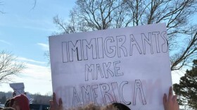 A student holds up a sign that says "Immigrants Make America" during a walkout protest against ICE in Derby.