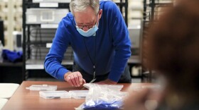 A Hamilton County election department employee handles ballots during the general election at the Hamilton County Board of Elections, Tuesday, Nov. 3, 2020, in Norwood, Ohio. 