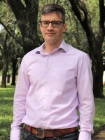 Man standing outside near trees, looking at camera