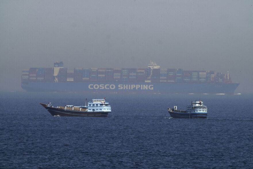 Two traditional dhows sail by a large container ship in the Strait of Hormuz Friday, May 19, 2023. (AP Photo/Jon Gambrell)