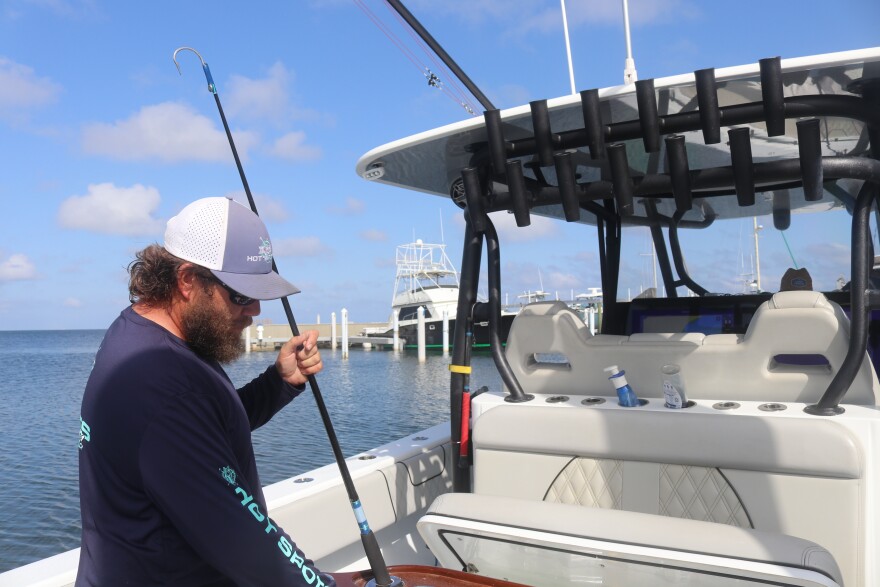 Tyler Massey, a charter boat captain, cleans his Hot Spots charter boat at the Santa Rosa Yacht & Boat Club on Friday, May 16, 2025. Kylie Williams/WUFT News