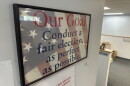 A framed voting sign reads,"Our Goal: Conduct a fair election, as perfect as possible."