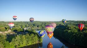 A group of hot air balloons rises over the Suncook River