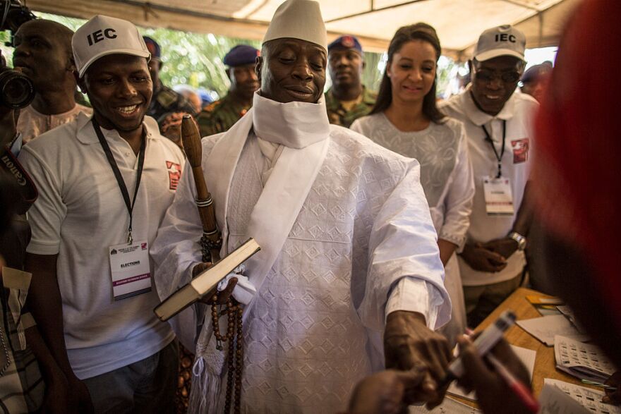 Incumbent Gambian President Yahya Jammeh (center) has his finger inked before casting his marble in a polling station during the presidential election.