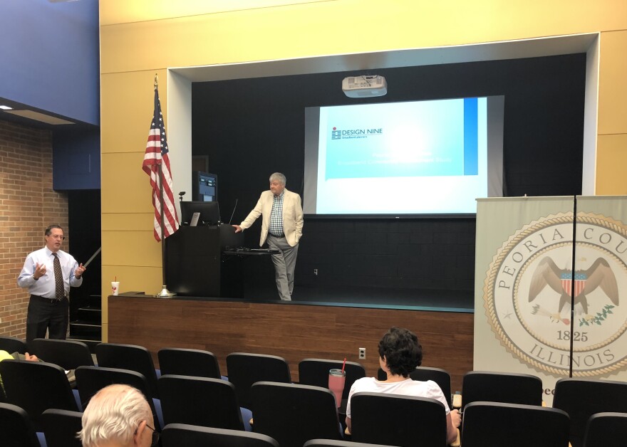 Peoria County Administrator Scott Sorrell, left, discusses the preliminary results of a countywide broadband feasibility survey and study as Jack Maytum, Senior Business for Design Nine, listens from the stage during a presentation at Illinois Central College's Peoria Campus.