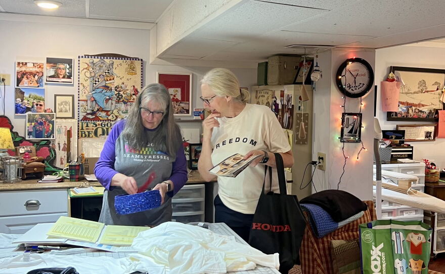Pat Cochran shows Patty Luther the supplies she uses to make shirts for cancer patients. She hosts 'zipper schools' like this for anyone who reaches out to her.