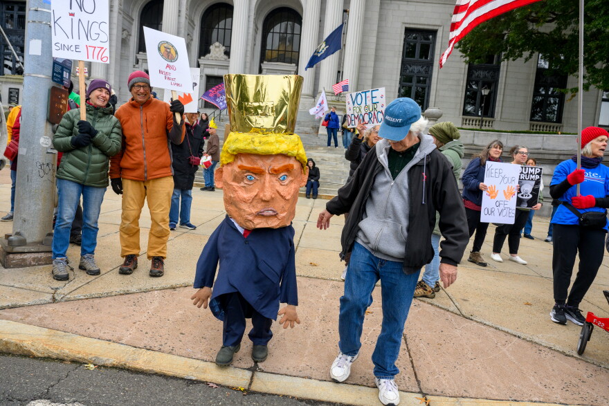 HARTFORD, CONNECTICUT - OCTOBER 17: A Donald Trump puppet crosses Capitol Avenue as NoKings protestors demonstrate outside the Connecticut State Capitol in Hartford, Connecticut on October, 17, 2026. (Mark Mirko/Connecticut Public)