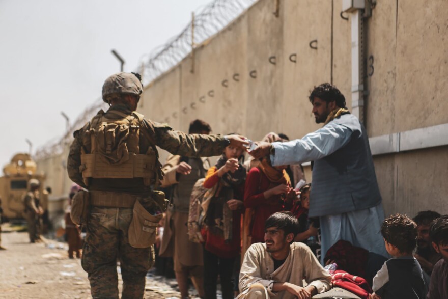KABUL, AFGHANISTAN - AUGUST 21:  In this handout provided by the U.S. Marine Corps, a Marine with the 24th Marine Expeditionary unit (MEU) passes out water to evacuees during the evacuation at Hamid Karzai International Airport during the evacuation on August 21, 2021 in Kabul, Afghanistan. The U.S. military is assisting in the evacuation effort.  (Photo by Isaiah Campbell/U.S. Marine Corps via Getty Images)