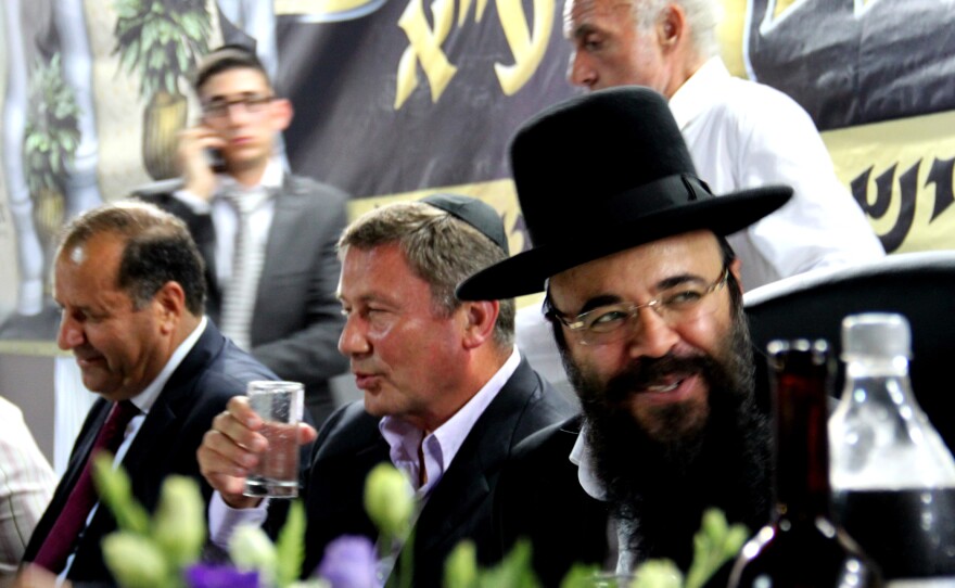 Ifargan, right, sits next to businessman Nochi Dankner, center, at an annual gala in Netivot, Israel, that honors the rabbi.