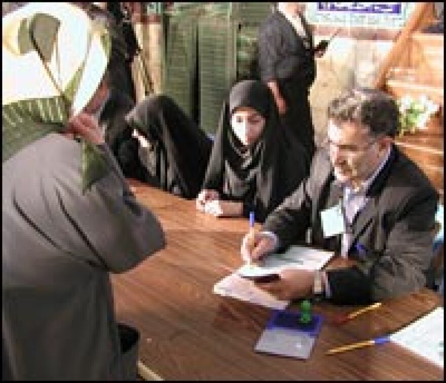 An election official checks a voter's documents at the Islamic Guidance Hall.