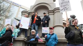 Protestors stand outside the Indiana Statehouse on Saturday, April 5 protesting against President Trump and his policies. The protest drew hundreds to Indianapolis, and thousands throughout the U.S. (Farrah Anderson / WFYI)
