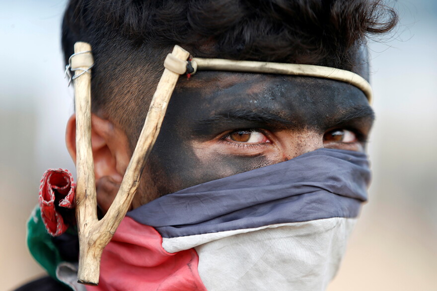 Palestinian demonstrator with a slingshot looks on during a protest against U.S. embassy move to Jerusalem and ahead of the 70th anniversary of Nakba, at the Israel-Gaza border, east of Gaza City May 14, 2018.