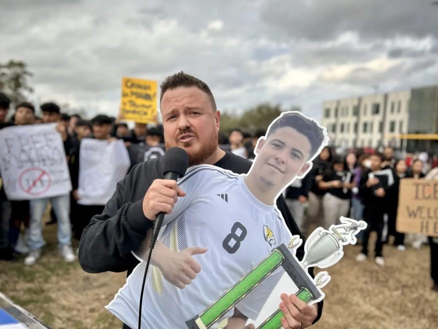 Miguel Gusar, the soccer coach at Sam Houston Math, Science, and Technology Center, holds a cutout of student Mauro Henriquez during a protest on Tuesday, Feb. 3, 2026, in Houston.
