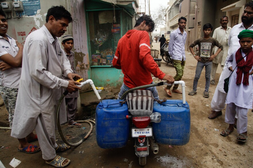 A young man fills the jerrycans tied to his motorbike with water in the Korangi slum.