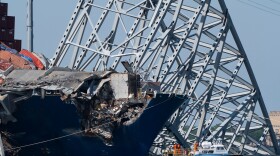 FILE - A boat moves past the bow of the container ship Dali prior to the detonation of explosive charges to bring down sections of the collapsed Francis Scott Key Bridge resting on the Dali, May 13, 2024, in Baltimore. (AP Photo/Mark Schiefelbein,File)