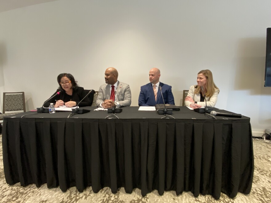 Four panelists sit at a table at the forum.