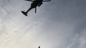 a person being hoisted through the air by a helicoper