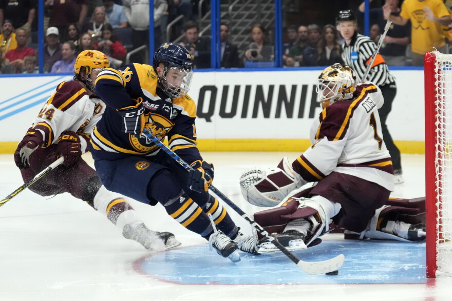 Quinnipiac forward Jacob Quillan scores the game-winning goal past Minnesota goaltender Justen Close during overtime of the championship game in the Frozen Four NCAA college hockey tournament Saturday, April 8, 2023, in Tampa, Fla.