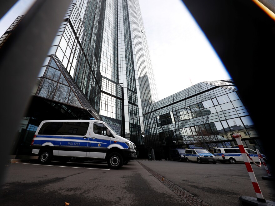 Police vehicles are parked in front of Deutsche Bank headquarters as roughly 170 officers, prosecutors and tax inspectors searched the bank's offices in and around Frankfurt, Germany, on Thursday.