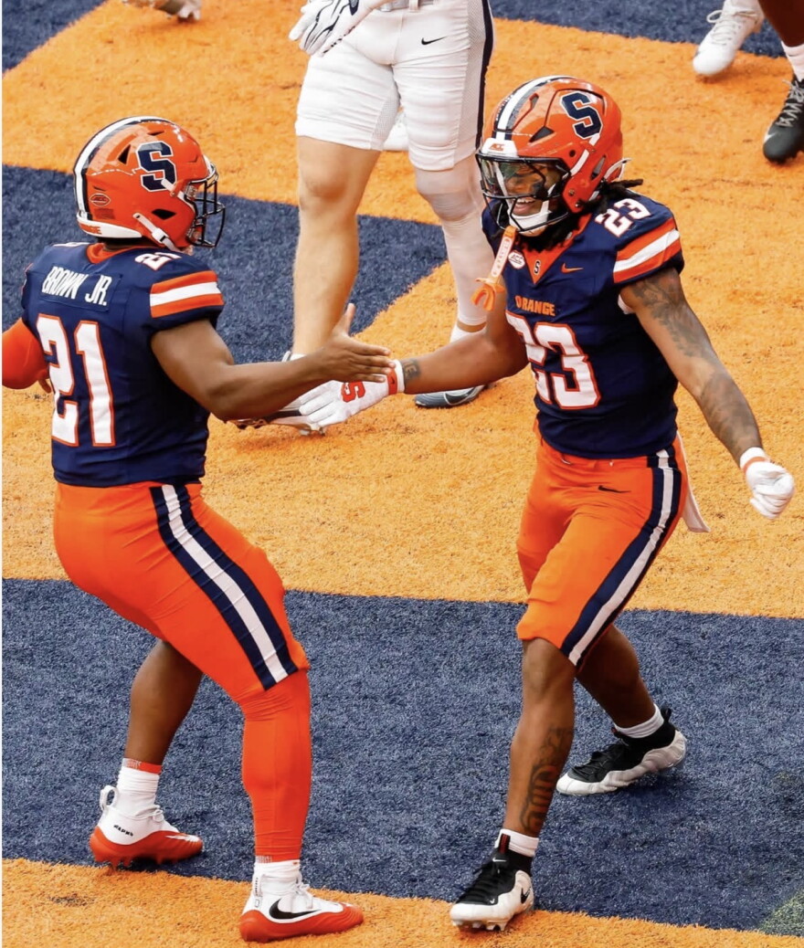 During a three-touchdown performance against UNH, SU running back Shavane Anderson Jr. (23, Blue) celebrates a touchdown with long snapper Fran Brown Jr. (21, Blue).