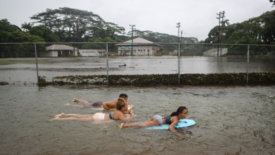 People bodyboard in floodwaters at a baseball field in Hilo, Hawaii, on Saturday after Hurricane Lane — now a tropical depression — drenched much of the state. The rainfall set a record at Hilo International Airport.