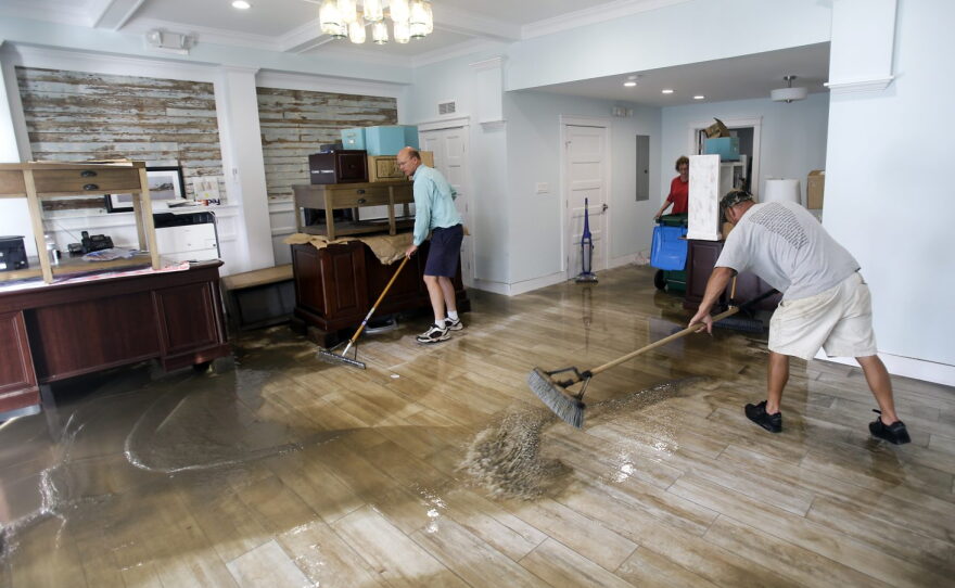 Shawn Stephenson, left, and Marshall Dimick clear water from a real estate office that was flooded by Hurricane Hermine Friday, Sept. 2, 2016, in Cedar Key, Fla. Hermine was downgraded to a tropical storm after it made landfall. (AP Photo/John Raoux)